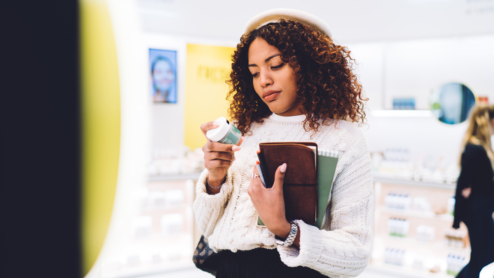A woman checks the label of a beauty product.